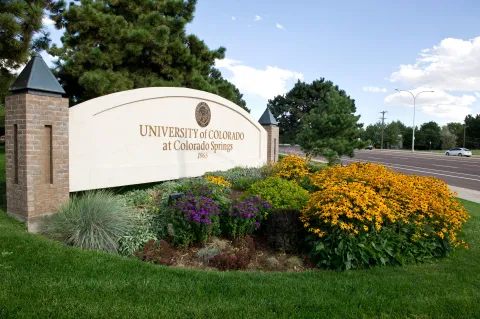 Picture of the UCCS Sign on campus with a flowerbed in front 