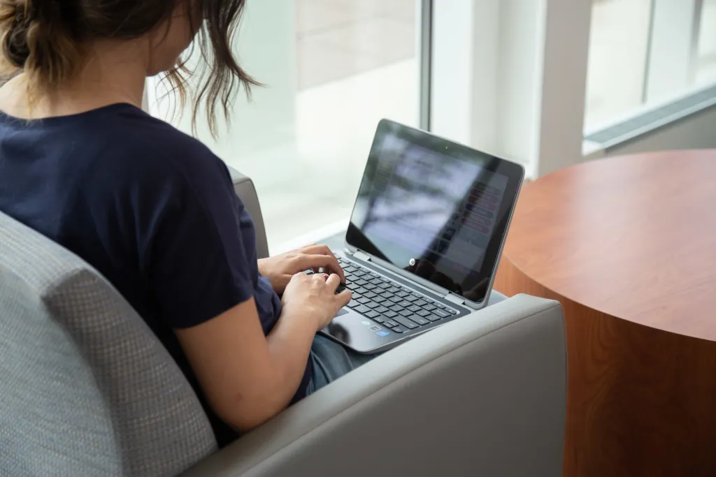 student working on a laptop while sitting in an armchair
